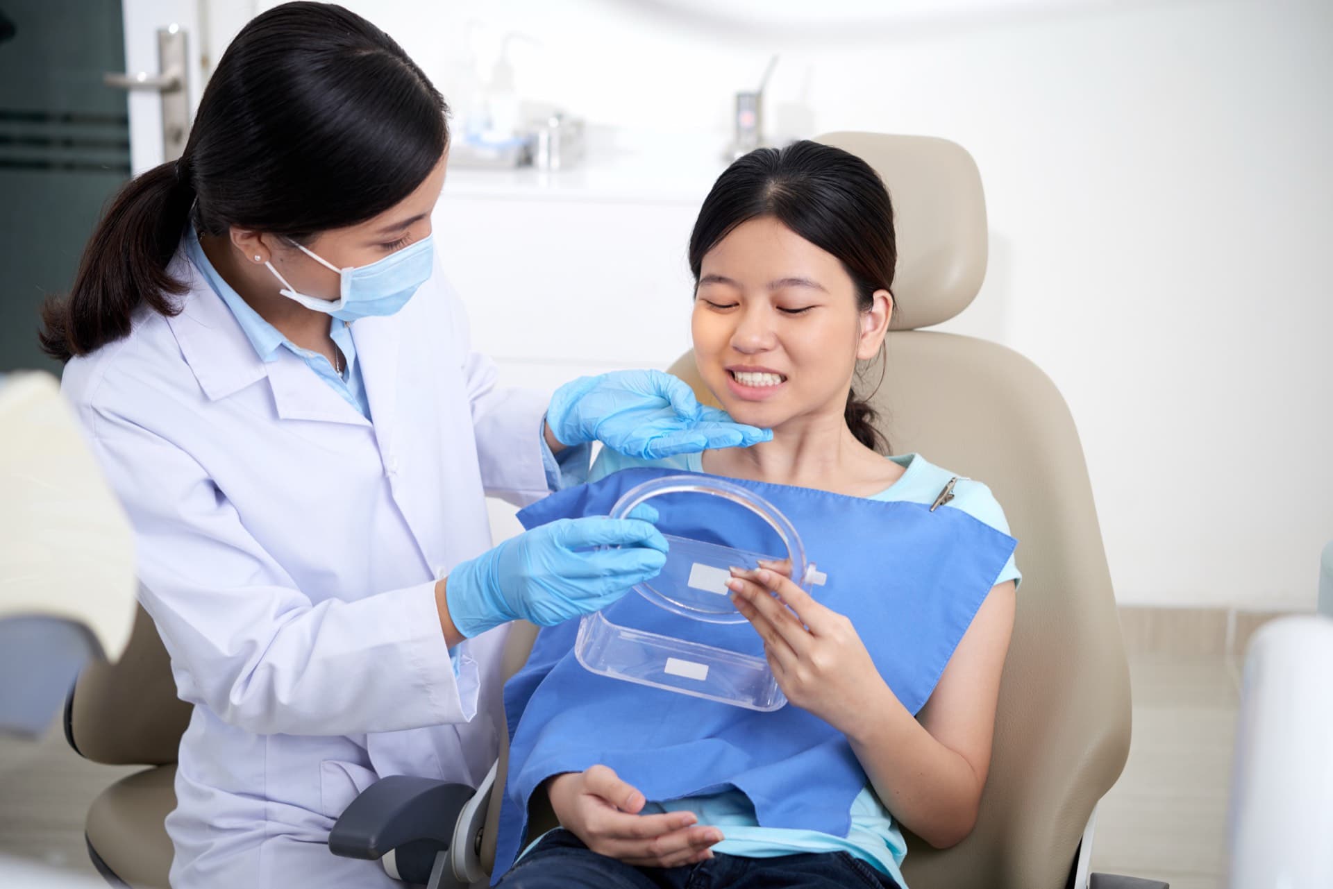 Dentist handing a seated patient a mirror to view her teeth
