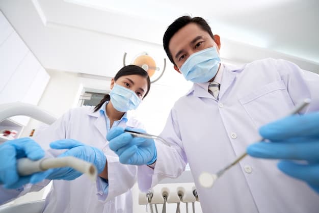 Two masked dental clinicians holding instruments beside a patient chair
