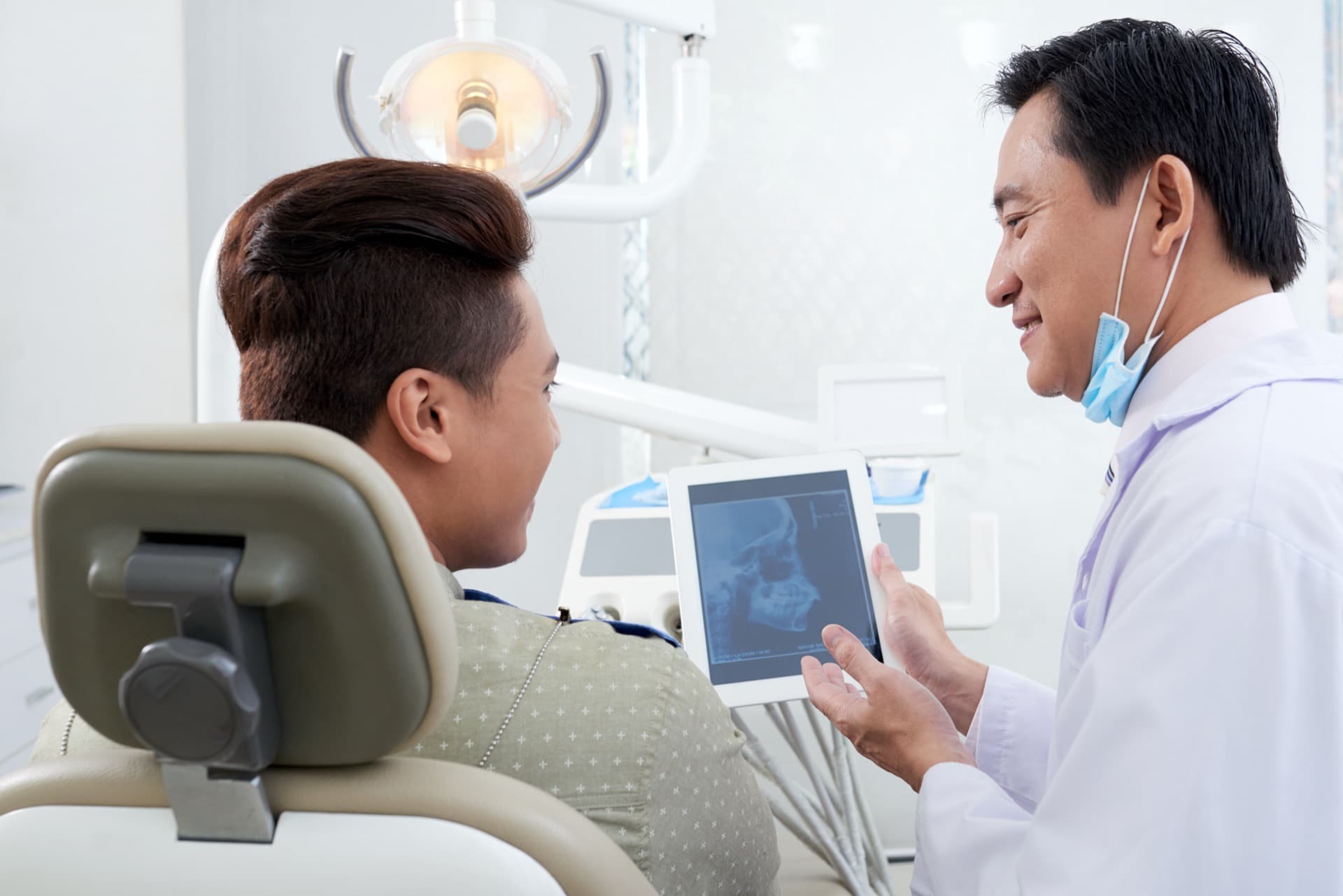 A dentist showing a patient a dental X-ray on a tablet