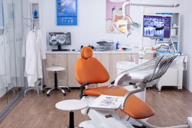 Empty dental treatment room with an orange chair and imaging screens