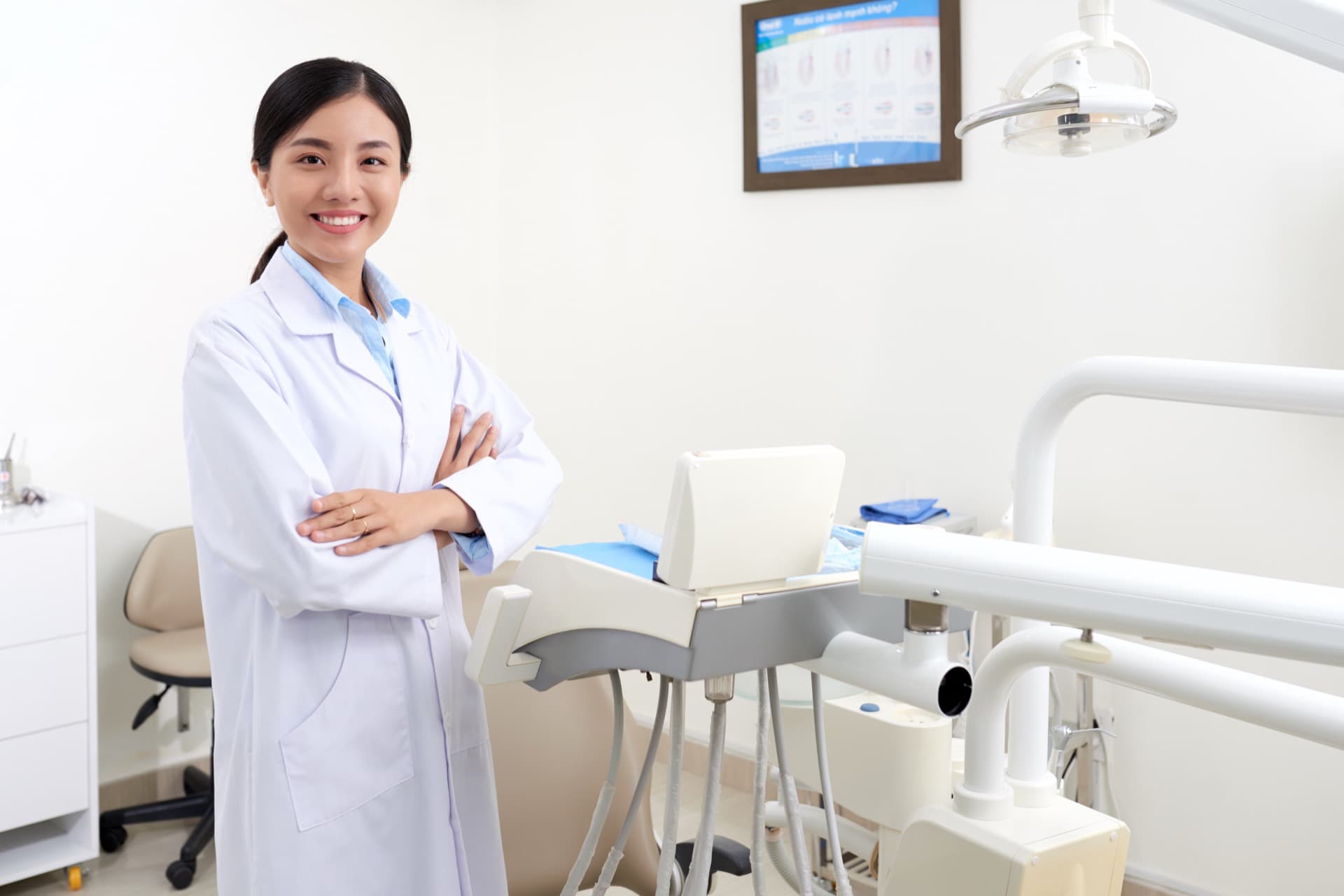 Woman dentist standing beside a dental chair in a bright treatment room