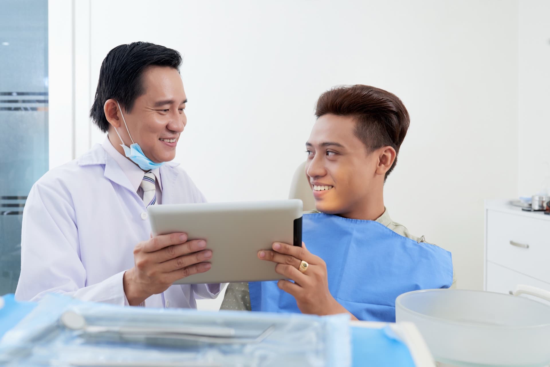 Dentist reviewing information on a tablet with a seated patient