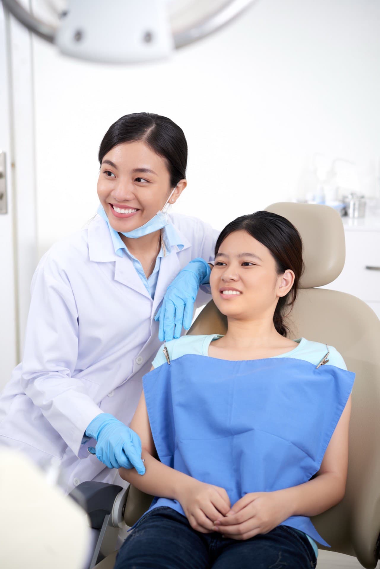 Dentist standing beside a smiling patient in a dental chair